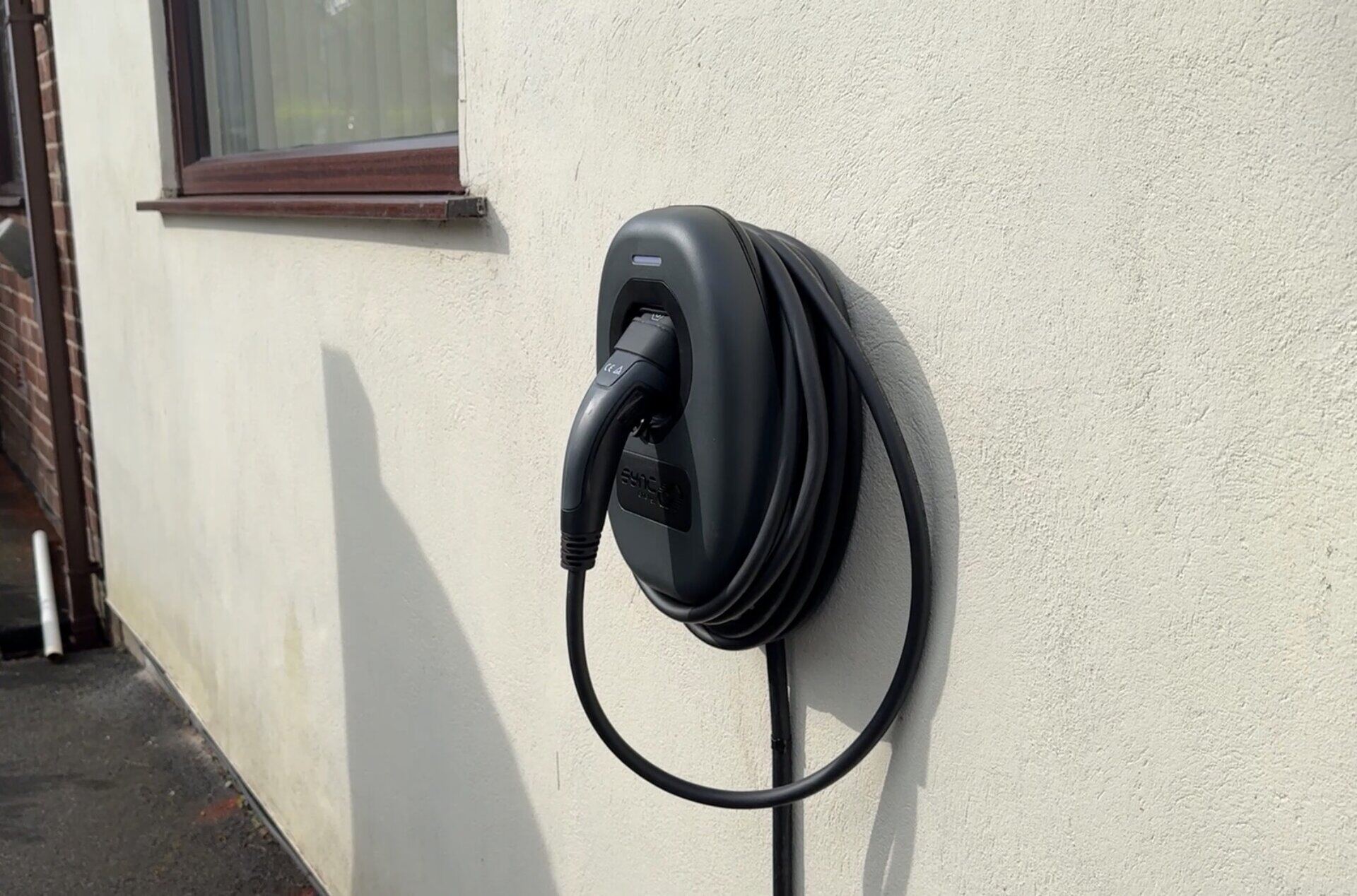 Sync EV home charger installed on a rendered exterior wall with neatly dressed cable management